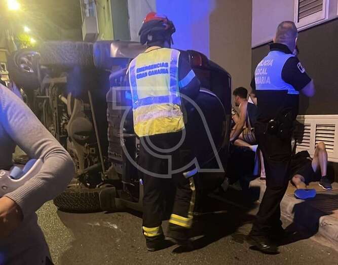 Bomberos y policías junto al vehículo volcado/TA.